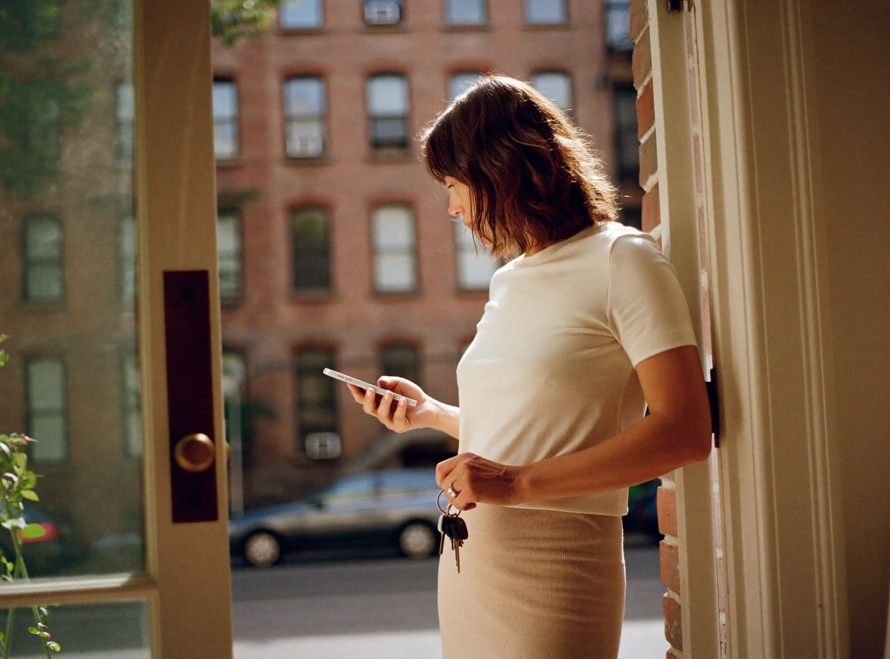 A landlord at the door of her building, reading her phone